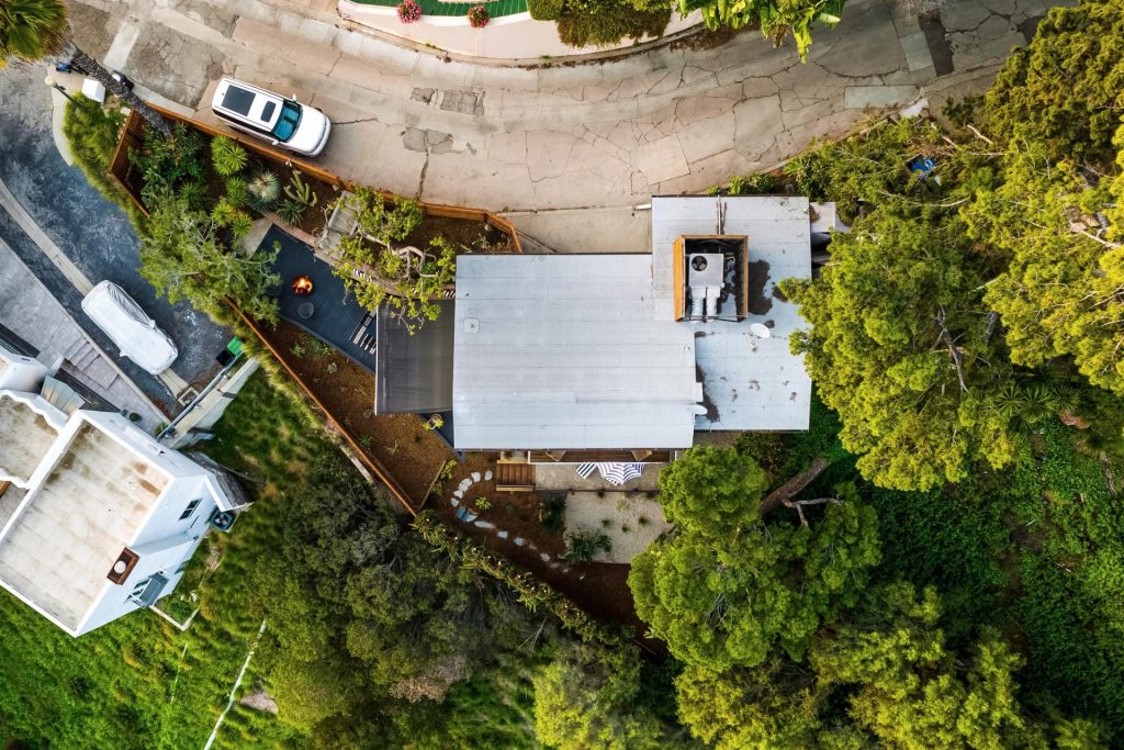 Above ground view of a house surrounded by dirt and greenery